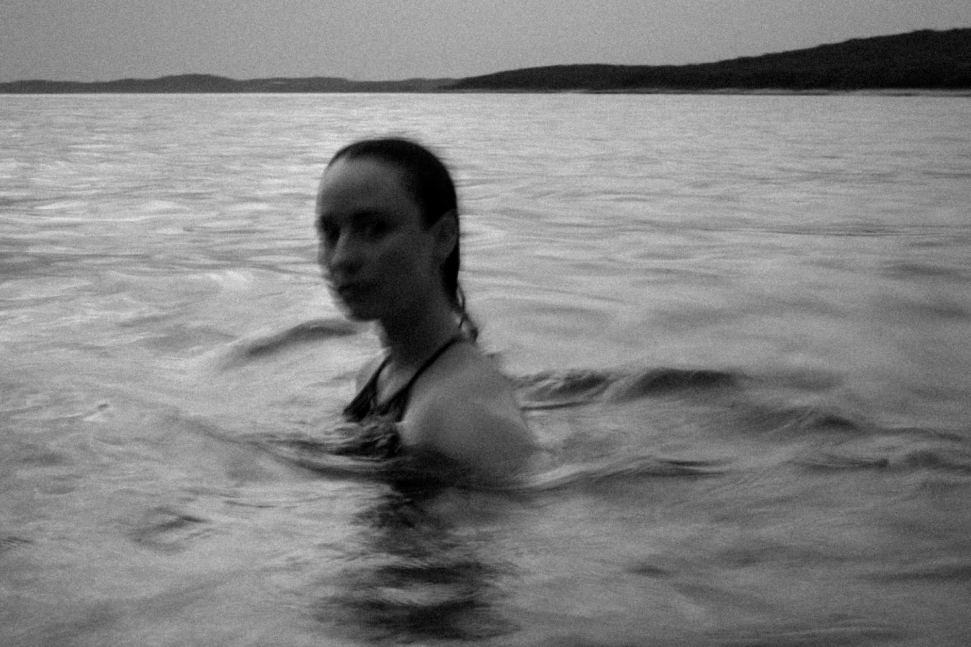 blurry black and white portrait of a woman swimming in the sea