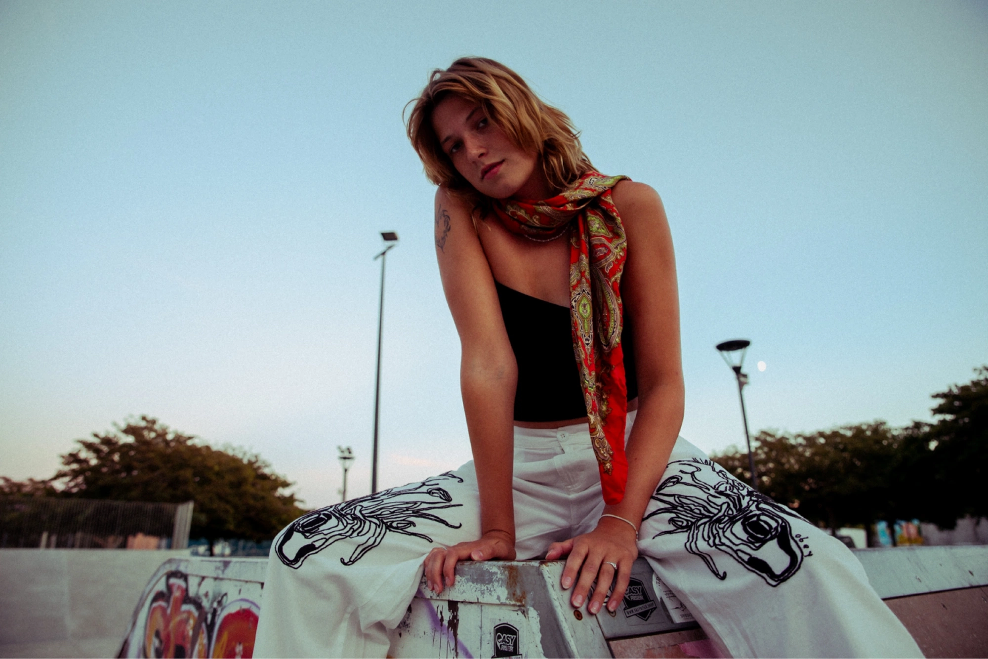 young woman sitting on a halfpipe on a skate park